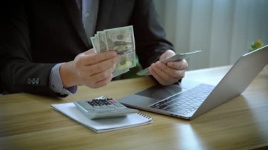 Yatırım için para say. İşadamı iş planlar, faiz oranları, vergiler, gelir, giderler, sermaye hesaplar.