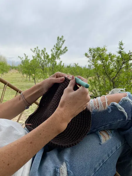 Kadın, doğal manzarayla çevrili bir güvertede tığ işi yapıyor. Yüksek kalite fotoğraf