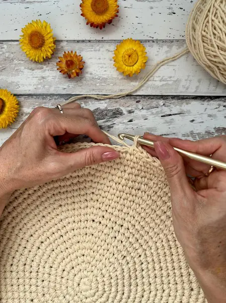 stock image Females hands crocheting on a wooden table decorated with flowers. High quality photo