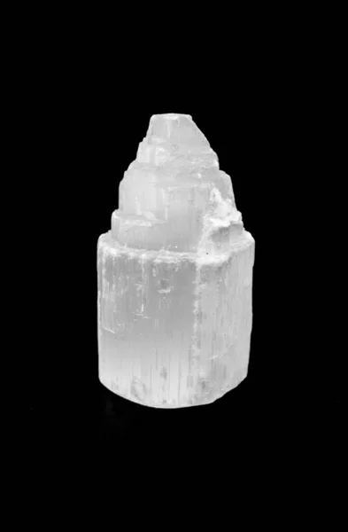 Selenite pillar wand crystal cluster isolated on a black background