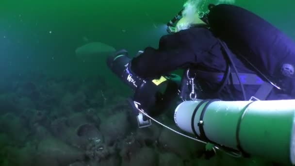水中考古学 水中スクーターを持つ探検家ダイバーは アンティーク難破船を表すアンフォラの山の上をゆっくりと泳ぐ — ストック動画