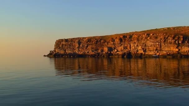 カメラはゆっくりとスネーク島の岩場に近づいています 日没の光 水の中の岩の反射 ウクライナ — ストック動画