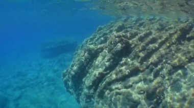 Titreyen güneş ışığının ışınlarında kayalık sualtı manzarası.