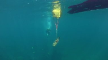 Underwater archeology: A bag of an underwater lifting system attached to an antique Greek stone anchor on the sea surface next to the boat.