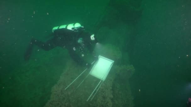 水中文化遺産 難破船の潜水艦のデッキには この物体が国家保護下にあることを知らせる標識を設置する準備をしているダイバー — ストック動画