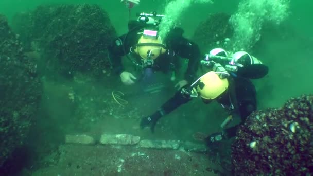 水下考古研究 潜水者讨论了躺在岩石上的古希腊铅锚的碎片 — 图库视频影像