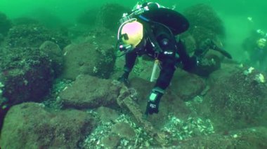 Sualtı arkeolojik araştırmaları: Ön planda bulunan bir dalgıç, kurtarılmış bir antika Yunan dayanağını gösteriyor.