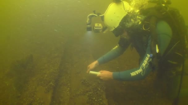 水中考古学研究 科学者ダイバーは川の底に横たわっている18世紀の木製の容器を調べます — ストック動画