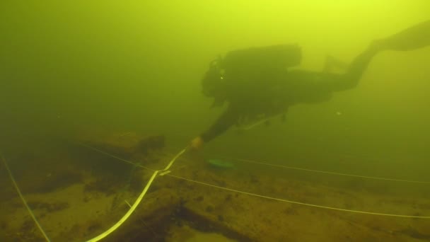 水中考古学研究 科学者のダイバーは 川の底に横たわっている18世紀の木製の船の計画を立てます — ストック動画