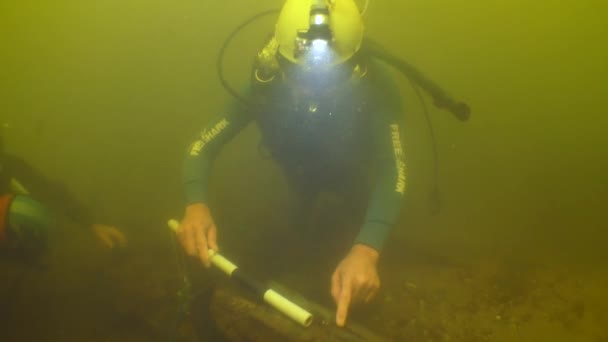 水中考古学的研究 ダイバーは 川の底に横たわる18世紀の木造船の断片を検査する — ストック動画