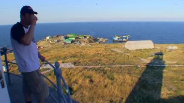 Erkek bir turist adayı Yılan Adası 'nın deniz fenerinin gözlem güvertesinden izliyor. Karadeniz, Ukrayna.