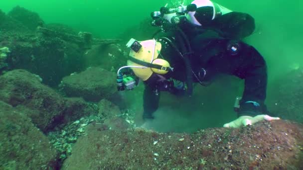 A diver with a metal detector explores the seabed. — Vídeos de Stock