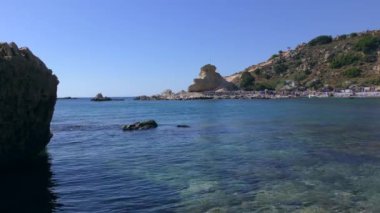 Akdeniz adasının kayalık sahillerinde donanımlı bir plajı olan rahat bir koy. Rodos, Stegna.