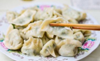 Çubuklar haşlanmış Çin mantılarını (Jiaozi) bir tabaktan alır.. 