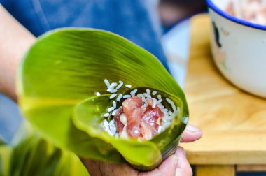 Yapışkan pirinç ve domuz dolgularıyla dolu bir el yaprağı. Zongzi yapmak için. Ejderha Teknesi Festivali için geleneksel Çin pirinç köftesi..