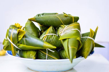 Zongzi, arka planda beyaz bir plakaya yerleştirilmiş. Zongzi, Ejder Gemisi Festivali (Duanwu Festivali) için geleneksel Çin pirinç köftesidir.). 