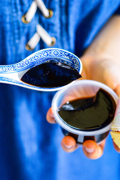 A woman hands holding black Chinese herb jelly called Guiling Gao, a Chinese herb-made dessert.  