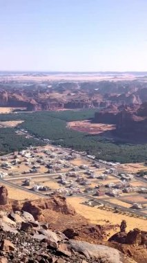 Harrat bakış açısıyla Alula 'nın panoramik görüntüsüne sahip dikey görüntüler, Suudi Arabistan' ın Alula kentindeki kaya dağlarıyla çevrili evleri ve hurma ağaçlarını gösteriyor..