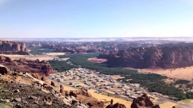 Harrat bakış açısından Alula 'nın panoramik görüntüsü Suudi Arabistan' ın Alula kentindeki kaya dağlarıyla çevrili evleri ve hurma ağaçlarını gösteriyor.