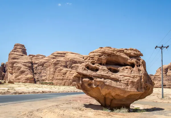 Suudi Arabistan 'da yol kenarında büyük bir kaya manzarası güneşli bir günde arka planda kaya dağları.  