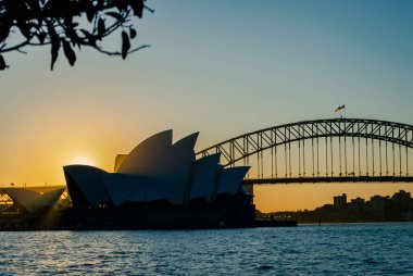 Sydney, Avustralya, 26 Temmuz 2023. Günbatımında Sydney Opera Binası ve Sydney Liman Köprüsü 'nün güzel rıhtım manzarası. 