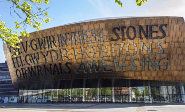 Cardiff, Birleşik Krallık, 20 Nisan 2019. Güneşli bir günde Galler Milenyum Merkezi 'nin dışı. Galce 'nin çevirisi:' İlham kaynağından cam gibi gerçek yaratmak '. 