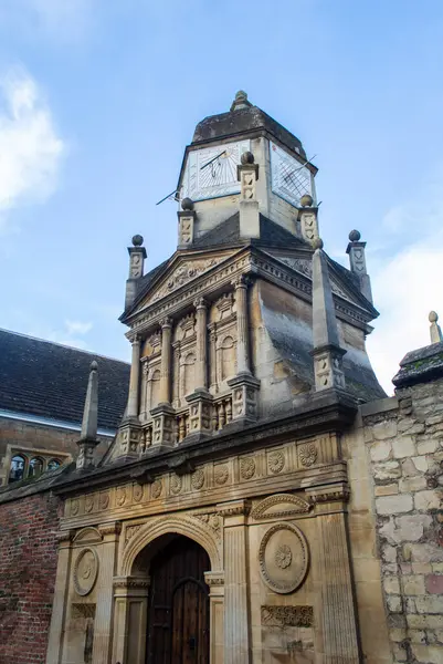 Cambridge, İngiltere, 7 Ocak 2022. Güneşli bir günde Cambridge şehrinde tuğla duvar ve eski saat kulesi olan bir cadde manzarası. 