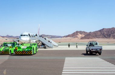 Alula, Suudi Arabistan, 5 Nisan 2024. Güneşli bir günde Alula havaalanındaki Katar Havayolları uçağına binen yolcuların görüntüsü.