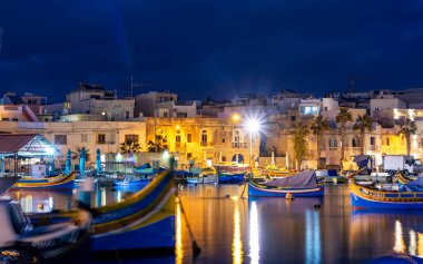 Marsaxlokk, Malta, 28 Şubat 2020. Marsaxlokk limanı. Geceleri renkli balıkçı tekneleri ve sokak ışıkları..  