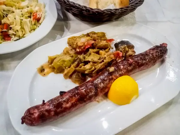 Yunanistan 'da yerel bir restoranda ızgara Yunan sosisi ve sebzeleri bir yemek masasına yerleştirildi.