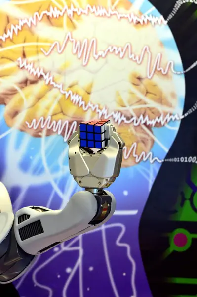 Londonderry, İngiltere. Şubat, 2017. Beyin bilimi ve sayısal sayıların soyut arka planına sahip bir Rubik Küpü tutan bir robot el.. 