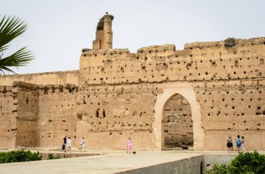 Marakeş, Fas, 8 Nisan 2023. Turistler Marakeş Badi Sarayı 'nın içinde kemer kapılı antik bir duvarın yanında duruyorlar..