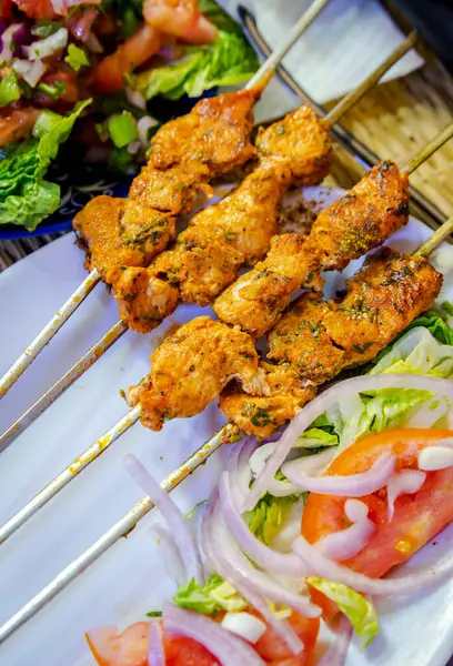 Marakeş 'teki bir restoranın yanında renkli salata ile beyaz bir tabağa yerleştirilmiş Fas usulü tavuk kebabı.