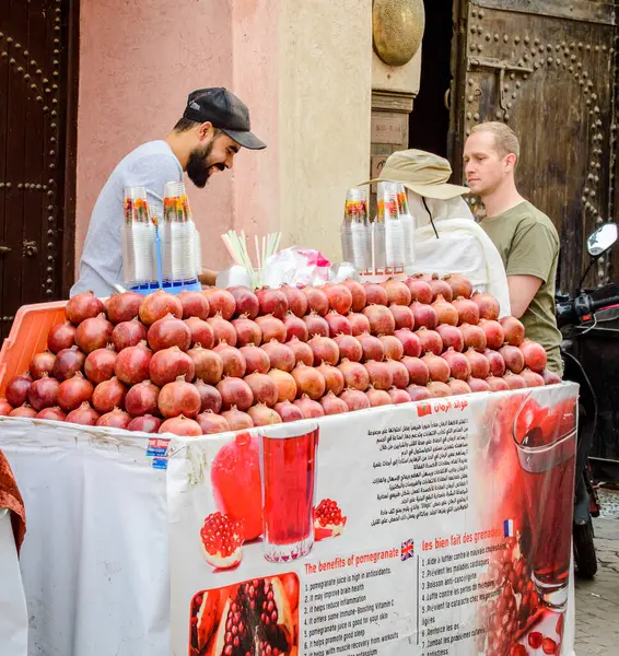 Marakeş, Fas, 8 Nisan 2023. Büyük gülümsemeli bir Morrokalı erkek satıcı güneşli bir günde Marakeş Medine 'deki turistlere taze nar suyu satıyor..