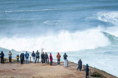 Nazare, Portekiz, 9 Mart 2025. Visistorlar güneşli bir günde Nazare 'de büyük dalgaları ve sörfü izliyorlar..