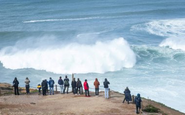 Nazare, Portekiz, 9 Mart 2025. Visistorlar güneşli bir günde Nazare 'de büyük dalgaları ve sörfü izliyorlar..