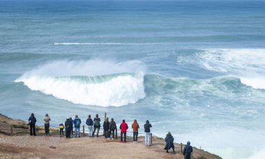 Nazare, Portekiz, 9 Mart 2025. Visistorlar güneşli bir günde Nazare 'de büyük dalgaları ve sörfü izliyorlar..