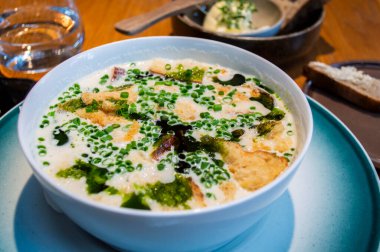 Geleneksel Norveç balık çorbasının genel manzarası, kremalı et suyu balık filetosu, ekmek ve Norveç 'teki yerel bir restorandan taze soğan ile servis edilir..