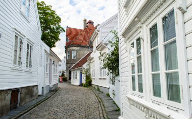 Stavanger, Norveç, 6 Haziran 2025. Gamle Stavanger Norveç 'in tarihi bölgesinin beyaz kereste evleri ve gün batımından sonra kaldırım taşı kaplı caddesi manzarası.