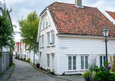 Stavanger, Norveç, 6 Haziran 2025. Gamle Stavanger Norveç 'in tarihi bölgesinin beyaz kereste evleri ve gün batımından sonra kaldırım taşı kaplı caddesi manzarası.