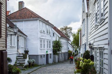Stavanger, 4 Eylül 2025. Gamle Stavanger Norveç 'in tarihi bölgesinin beyaz kereste evleri ve gün batımından sonra kaldırım taşı kaplı caddesi manzarası.