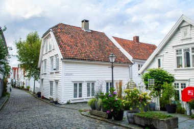 Stavanger, 4 Eylül 2025. Gamle Stavanger Norveç 'in tarihi bölgesinin beyaz kereste evleri ve gün batımından sonra kaldırım taşı kaplı caddesi manzarası.