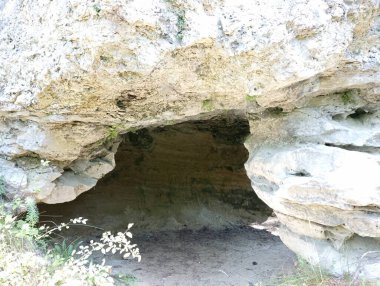 Beyaz kumlu bir kayanın içinde bir mağara. Dağ mağarası. Dağ yamacındaki mağaranın girişi..