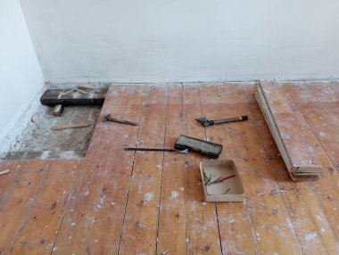 Dismantling the floor. Repair of the floor in the room. Scattered construction tools during repair work.