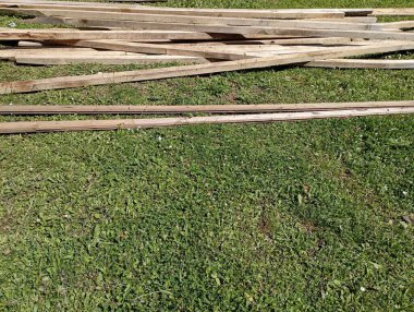 Tahta levhalar ve marangozluk endüstrisinden gelen diğer malzemeler çimenlere saçılmıştı..