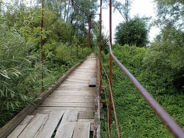 木制悬索桥从被时间和自然条件破坏的旧木板上的木制过渡 过河的危险桥 — 图库照片
