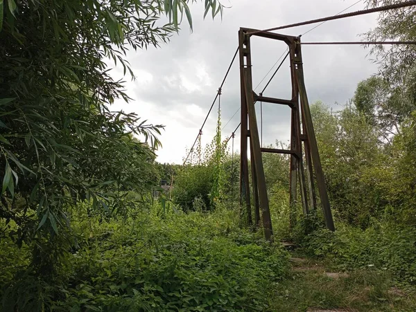 stock image A support on which a rope for a suspended pedestrian bridge is stretched. Metal construction of a suspension bridge across the river.