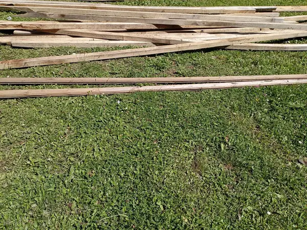 木工業からの木製のスラットおよび他の材料は草の上に散らばっています — ストック写真