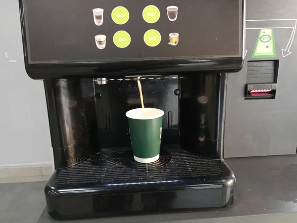 ストリート自動販売機からコーヒーを買う コーヒーは緑色の紙コップに注ぎ込まれています コーヒー醸造と消費のトピック — ストック写真