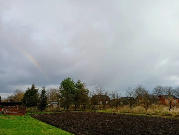 A rainbow over the village. Landscape of the Ukrainian village after the rain. Autumn view of the house from the field.